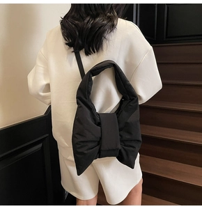 Detail view of black nylon tote bag with large bow design on a model back