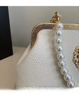 Close-up of golden vintage engraved metal clasp and white lychee texture leather bag