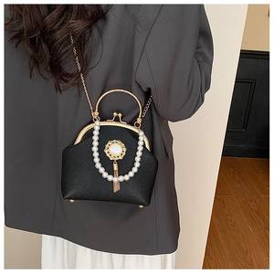 Detail of vintage black leather clutch with white pearl handle and gold tassel accents