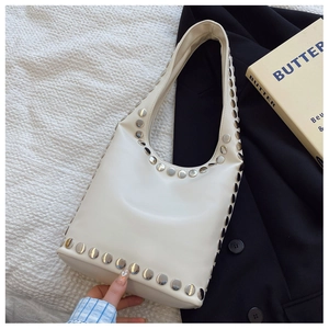 Detail der cremeweißen Schultertasche mit metallischen Silbernieten und glattem Lederfinish