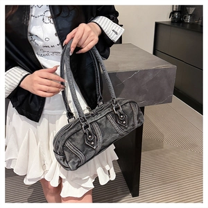 Detail of washed denim cylinder bag with contrast stitching and silver hardware