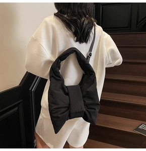 Detail of a black 3D puffer bow shoulder bag featuring a glossy texture and metal buckle