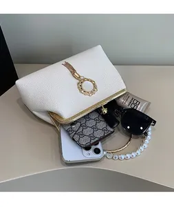 Spacious interior of white textured leather evening bag with pearl chain and gold tassel