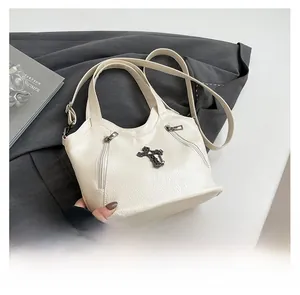 Detail of white tote bag featuring black metal cross and textured lychee leather finish