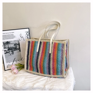 Detail of colorful woven straw tote with rainbow stripes and white leather handles