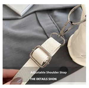 Detail of adjustable white lychee pattern leather shoulder strap with silver metal buckles