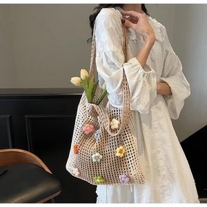 Détail d'un sac cabas en maille beige avec motifs de fleurs colorées crochetées à la main