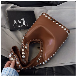 Detailaufnahme der braunen glänzenden Ledertasche mit silbernen Metallnieten am Rand