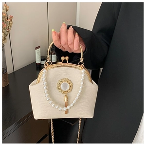 Detail of beaded pearl handle and golden tassel on a vintage cream shell handbag