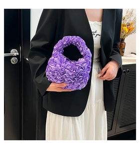 Detail showing purple pleated ruffled satin handbag with elegant layered lace texture