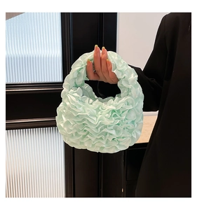 Detail of mint green pleated lace handbag featuring elegant ruffled layers and satin finish