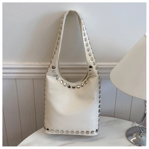 Detail der cremeweißen Hobo-Tasche mit silbernen Nieten auf einem Marmortisch
