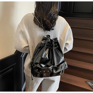 Detail of black glossy drawstring hobo bag with silver rivets and metal chain straps