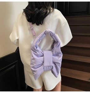 Detail of light purple oversized bow shoulder bag with textured fabric on a model