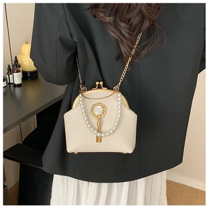 Detail of beaded cream shell bag with pearl chain and metallic gold tassel on shoulder