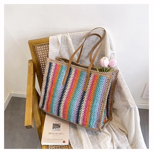 Detail of colorful woven straw tote with brown leather handles and striped pattern