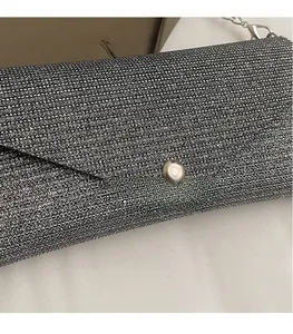 Detail of silver sequin evening clutch bag with metal chain strap and round snap button