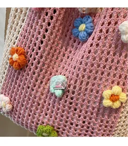 Détail du sac cabas en maille crochetée rose et blanc avec motifs de fleurs colorées