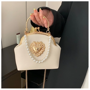 Detailed close-up of beaded ivory shell bag with golden heart emblem and metal handle