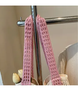 Gros plan détaillé de la bandoulière en tricot rose sur un sac cabas ajouré