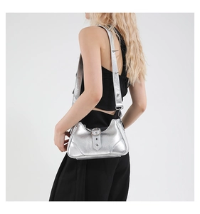 Détail du sac argenté métallisé avec pointes punk sur la large bandoulière style Y2K