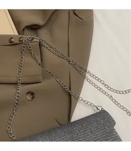 Detail of silver glitter crossbody bag with metallic chain strap on professional blazer