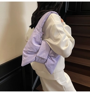 Rear view of a model wearing a soft purple oversized bow-shaped nylon shoulder bag