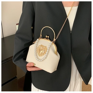 Detail of baroque pearl shell bag with gold heart relief and metallic clasp handle