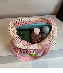 Vue intérieure d'un grand cabas en crochet rose et blanc contenant des objets du quotidien
