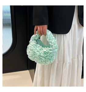 Detail of mint green pleated lace handbag with ruffled mesh fabric and smooth satin texture