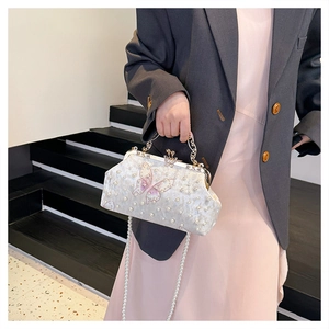 Détail de broderie papillon élégante et de perles sur un sac de soirée blanc