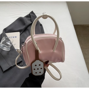 Macro detail of macaron pink crossbody bag with bicolor handles and shovel charm