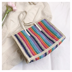 Detail of the colorful rainbow straw woven tote bag texture and cream faux leather handle
