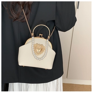 Detail of beaded evening bag with golden heart plaque and elegant pearl handle strap