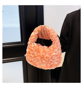 Detail of peach pink pleated satin handbag with ruffled lace design for women