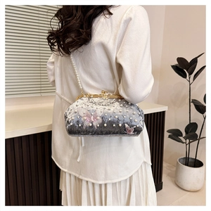 Détail de la pochette en velours gris avec bandoulière en perles et broderie papillon