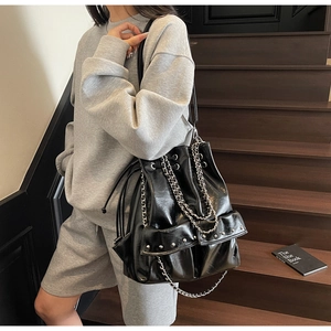 Detail of black oil wax leather bucket bag featuring silver chains and rivet accents