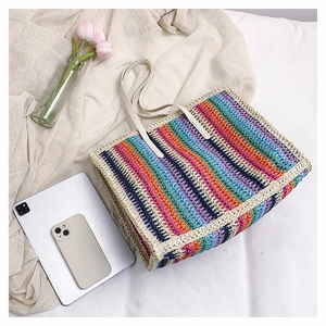 Close-up of rainbow striped straw tote bag with woven texture and cream handles