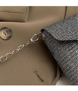 Close-up of shiny silver evening clutch with polished metal hook and chain strap detail