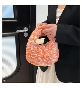 Close-up of ruffled peach tulle handbag detail featuring glossy satin pleats texture