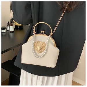 Detail of cream leather shell bag with gold heart relief and pearl handle accessory