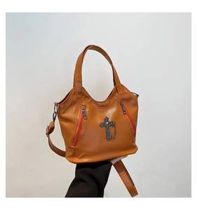 Close-up of caramel retro tote bag featuring metallic cross pendant and zipper details