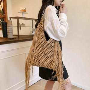 Handwoven khaki hollow mesh tote bag with long tassels and black leather shoulder strap