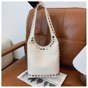 Detailansicht der weißen Hobo-Tasche mit silbernen Metallnieten auf einem Ledersofa