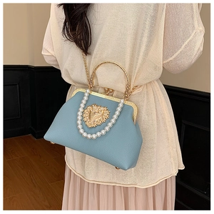 Close-up of light blue leather handbag with golden heart relief and pearl chain detail