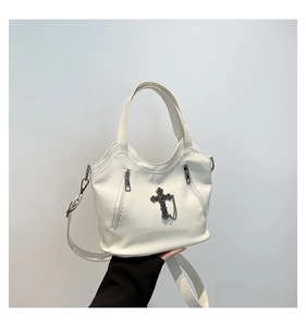 Detail of white cross tote bag showing textured leather and punk silver metal chains