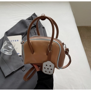Macro shot of brown retro Boston handbag with blue contrast trim on a gray suit jacket