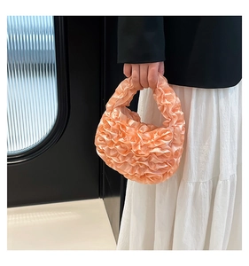 Detail of peach ruffled handbag showing high-density pleated fabric and satin luster