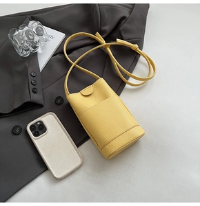 Détail du mini sac à bandoulière en cuir litchi jaune avec poche avant pour téléphone