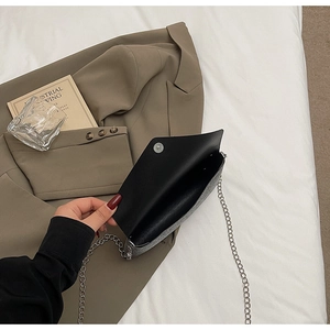 Detail view of the silver sequin chain bag showing the magnetic buckle and black interior